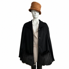 Load image into Gallery viewer, A black wool cloak with fox trimming on the pockets, featuring a classic cape shape with press-stud fastening, displayed on a mannequin with a tan hat and a light-colored shirt.