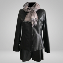 Load image into Gallery viewer, A black leather jacket with a stand collar and front pockets, displayed on a mannequin with a grey scarf wrapped around the neck.