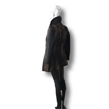 Load image into Gallery viewer, A black short goat fur jacket on a mannequin, featuring a straight silhouette with notched lapels, buttons, and a lining. The mannequin is dressed in a similar style with leather.