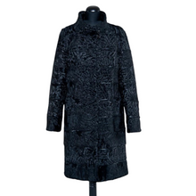 Load image into Gallery viewer, Black astrakhan knee-length coat with decorative textile inserts, stand collar, front pockets, and fur hooks fastening. It is displayed on a mannequin with a visible label.
