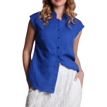 Load image into Gallery viewer, A woman wearing a blue sleeveless linen blouse with front buttons and decorative seams, paired with a white skirt.