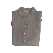 Load image into Gallery viewer, A woman wearing a blue, sleeveless, button-up linen blouse with decorative seams and a collar.