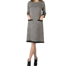 Load image into Gallery viewer, A woman wearing a knee-length checkered linen dress with long sleeves, paired with black ankle boots.