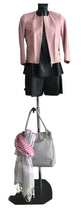 Load image into Gallery viewer, Mannequin wearing a pink jacket and black skirt with a gray handbag and pink scarf on a white background