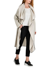 Load image into Gallery viewer, A long beige linen cardigan with a loose fit, displayed on a model who is showing the front and back of the garment.
