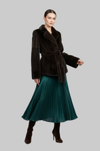 Įkelti nuotrauką į galerijos peržiūros programą, A model is shown wearing a dark brown fur wrap jacket with a matching belt, paired with a pleated teal green midi skirt and dark brown heeled boots, set against a solid gray background.
