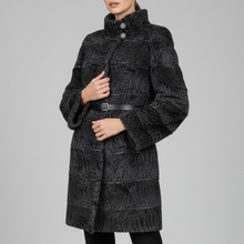 Įkelti nuotrauką į galerijos peržiūros programą, A model stands against a light gray studio background wearing a black textured faux-fur coat with a high collar and a thin black belt, paired with black pants and black ankle boots.
