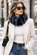 Load image into Gallery viewer, A woman wearing a cream coat with a dark navy blue fur collar, a white ribbed sweater, blue jeans, black sunglasses, and carrying a black shoulder bag on a city street.
