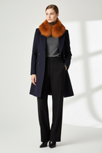 Įkelti nuotrauką į galerijos peržiūros programą, A model stands in a studio wearing a dark navy wool coat with a large orange-brown fur collar, a gray turtleneck, black wide-leg trousers, and black pointed shoes.
