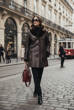 Įkelti nuotrauką į galerijos peržiūros programą, A woman walks down a cobblestone city street wearing a dark brown leather coat with a black fur collar, black trousers, black ankle boots, and holding a burgundy handbag.
