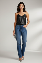 Load image into Gallery viewer, A woman modeling a black faux-leather camisole top and blue jeans against a light gray studio background.

