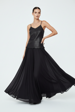 Load image into Gallery viewer, A model wearing a black sleeveless maxi dress with a structured faux-leather bodice and a flowing chiffon skirt, posed against a light gray studio background.
