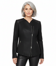 Load image into Gallery viewer, A woman with short gray hair wearing a black textured jacket with silver zipper details, paired with black pants, against a plain white background.
