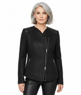 A woman with short gray hair wearing a black textured jacket with silver zipper details, paired with black pants, against a plain white background.