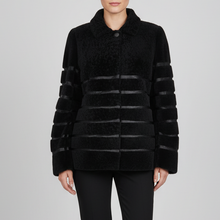 Įkelti nuotrauką į galerijos peržiūros programą, A model stands against a light gray studio background wearing a black textured jacket with horizontal striped panels on the sleeves and body, paired with black pants and black ankle boots.
