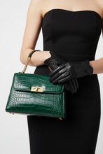 Įkelti nuotrauką į galerijos peržiūros programą, A model in a black strapless dress and black gloves holds a structured dark green crocodile-embossed handbag with gold hardware against a light gray studio background.
