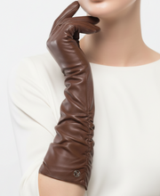Įkelti nuotrauką į galerijos peržiūros programą, A long, dark brown leather opera glove worn on a model's hand, shown against a clean white background. The glove features a gathered, ruched design and a small silver-tone logo button near the cuff.
