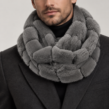 Įkelti nuotrauką į galerijos peržiūros programą, A close-up of a man wearing a chunky, textured gray faux-fur infinity scarf and a dark gray coat over a black turtleneck, set against a plain light gray studio background.
