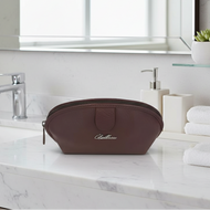 Brown travel pouch on a marble bathroom counter with a mirror and sink in the background