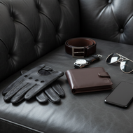 Leather gloves, wallet, sunglasses, and phone on a black leather couch