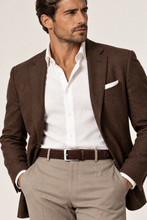 Load image into Gallery viewer, A man wearing a brown textured blazer over a white dress shirt, paired with beige trousers and a brown woven belt, photographed against a light neutral studio background.

