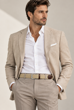 Load image into Gallery viewer, A man wearing a light beige textured blazer, matching trousers, a white dress shirt, and a beige woven belt, posed against a neutral beige background.
