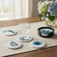 Coasters with tropical designs on a table with a glass of water and flowers.