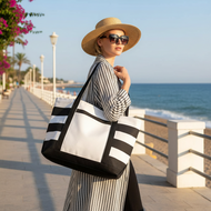 Woman with a black and white striped tote bag on a beach promenade.
