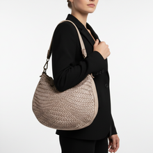 Load image into Gallery viewer, Person holding a woven beige handbag against a white background
