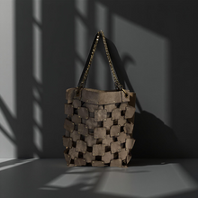 Load image into Gallery viewer, Woven handbag with chain handle on a dark background

