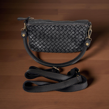 Load image into Gallery viewer, Black woven handbag with a strap on a wooden surface
