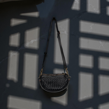 Load image into Gallery viewer, Black woven handbag on a dark textured background
