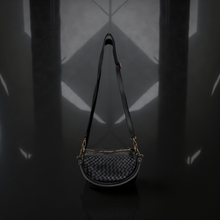 Load image into Gallery viewer, Black woven handbag on a dark surface with geometric light patterns
