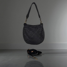 Load image into Gallery viewer, Black woven handbag on a reflective surface with a gray background
