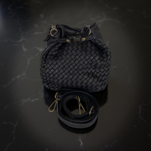 Load image into Gallery viewer, Black woven handbag with a strap on a dark marble surface
