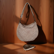 Load image into Gallery viewer, Woven handbag on a wooden surface with a wooden wall background
