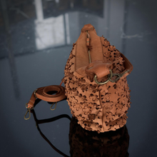 Load image into Gallery viewer, Brown leather bag with intricate cut-out design on a reflective surface
