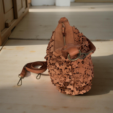 Load image into Gallery viewer, Brown leather bag with intricate cut-out design on a wooden floor.
