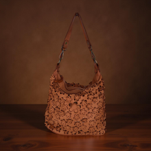 Load image into Gallery viewer, Brown leather handbag with floral patterns on a wooden surface and brown background
