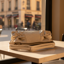 Load image into Gallery viewer, Folded beige leather bag on a table with a city street background
