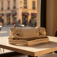 Folded beige leather bag on a table with a city street background