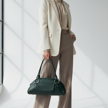 Įkelti nuotrauką į galerijos peržiūros programą, A woman stands in a bright studio setting wearing a cream blazer, beige blouse, taupe wide-leg trousers, and holding a dark green leather handbag.
