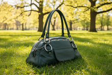 Load image into Gallery viewer, Green handbag on grass with trees in the background
