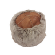 A beige sheepskin fur cap with a leather band on top.