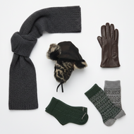 Collection of winter accessories including a scarf, hat, gloves, and socks on a white background