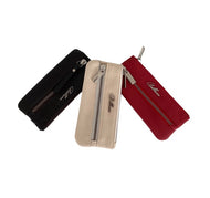 Three Italian leather key holders with zipper closures, in black, beige, and red colors, displayed side by side.