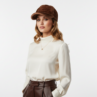 Woman wearing a white blouse and brown cap on a light gray background