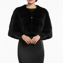 Įkelti nuotrauką į galerijos peržiūros programą, A model wearing a black long-sleeve faux-fur bolero jacket with a small gold button detail, paired with a matching black floor-length gown, against a plain white studio background.

