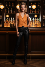 Įkelti nuotrauką į galerijos peržiūros programą, Woman in an orange top and black leather pants standing in a bar setting.
