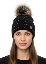 Load image into Gallery viewer, Black beanie with pom-pom worn by a model on a white background

